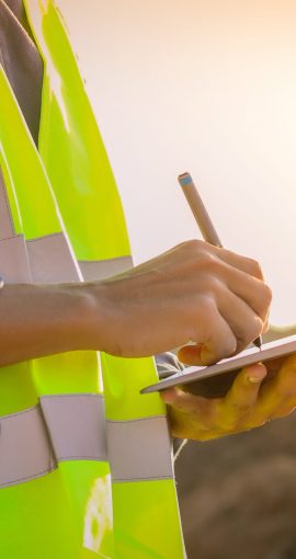 Asian engineer with hardhat using  tablet pc computer inspecting and working at construction site